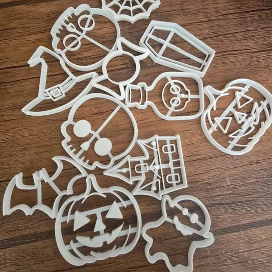 12-piece Halloween cookie cutter set with ghost, pumpkin, bat, and witch hat shapes on rustic baking tray
